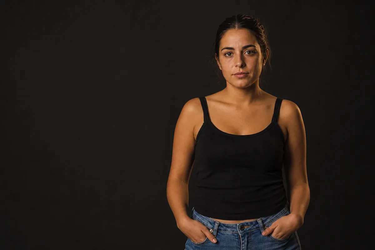 Modelo joven de frente a cámara con los hombros nivelados y las manos en los bolsillos