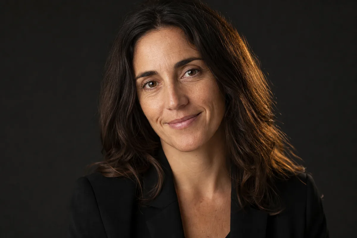 Retrato profesional de mujer con blazer sobre fondo neutro