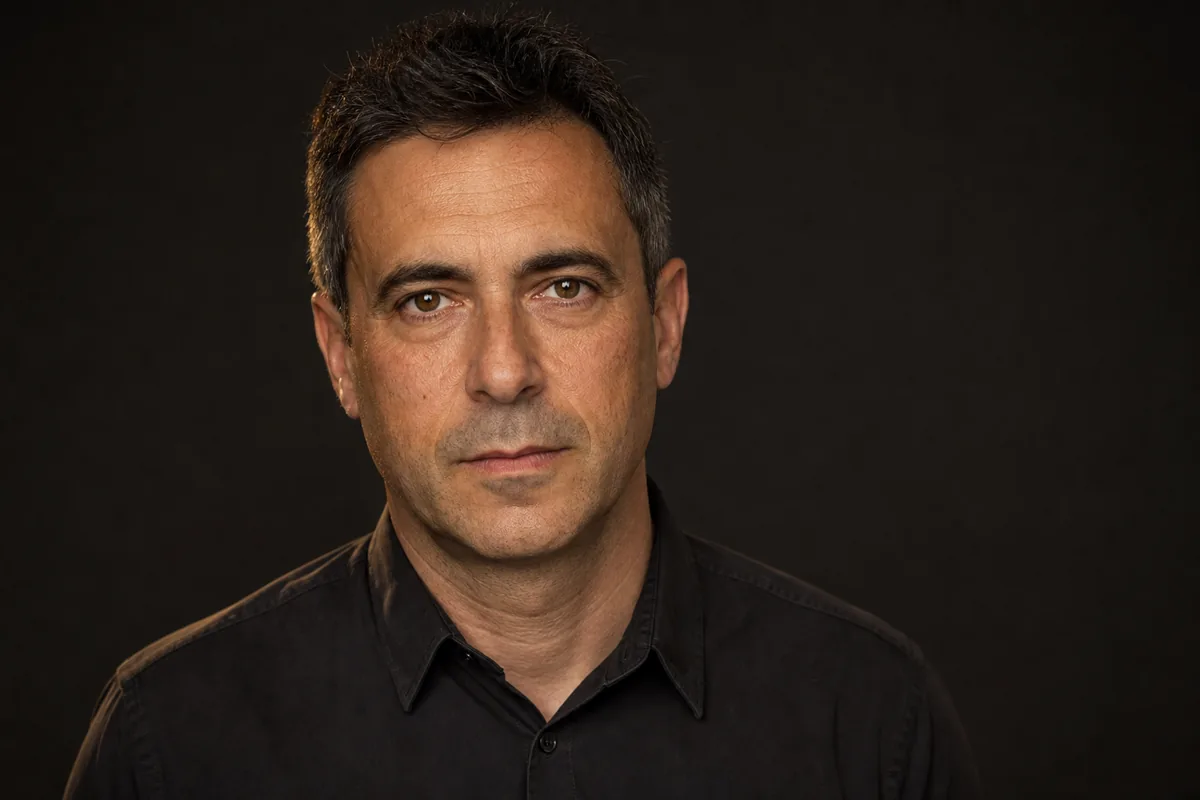 Headshot de hombre sobre fondo gris medio con el cuello de la camisa asentado