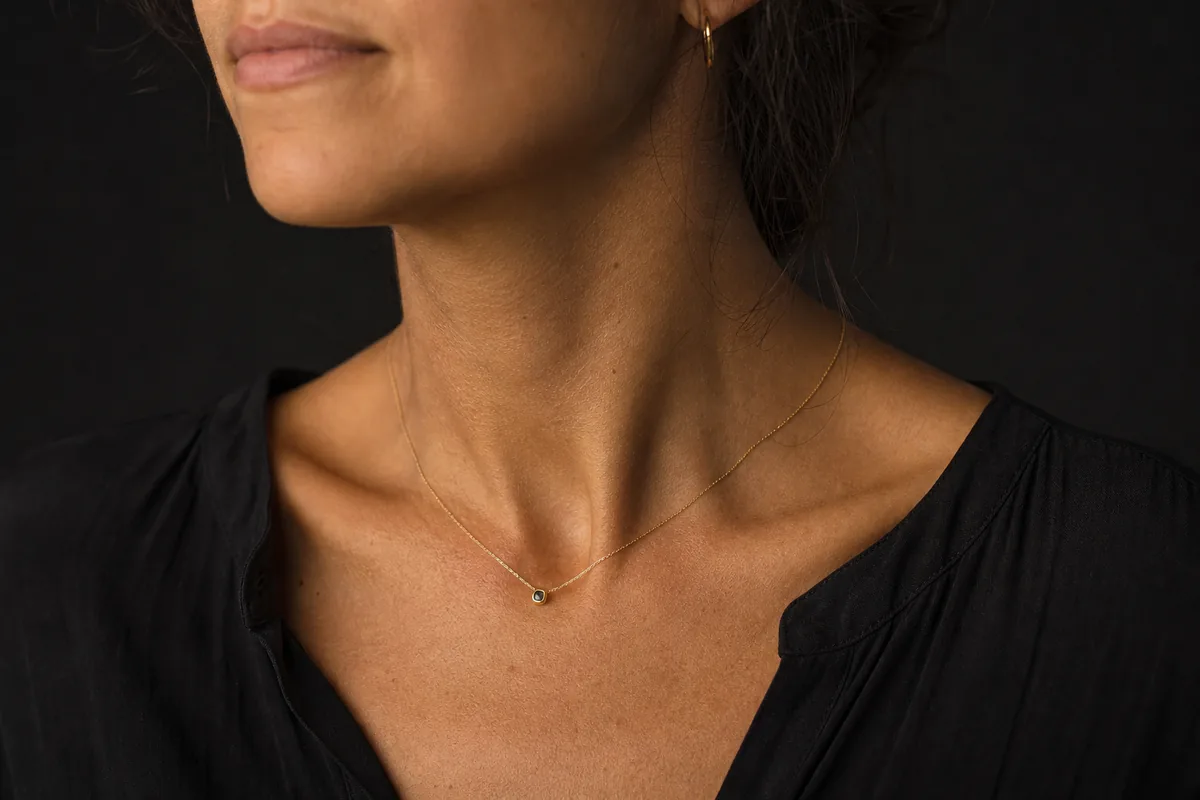 Detalle del cuello con una cadena fina y colgante pequeño