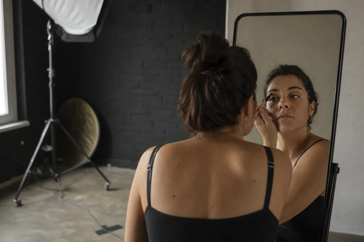 Clienta terminando su maquillaje frente al espejo antes de la sesión