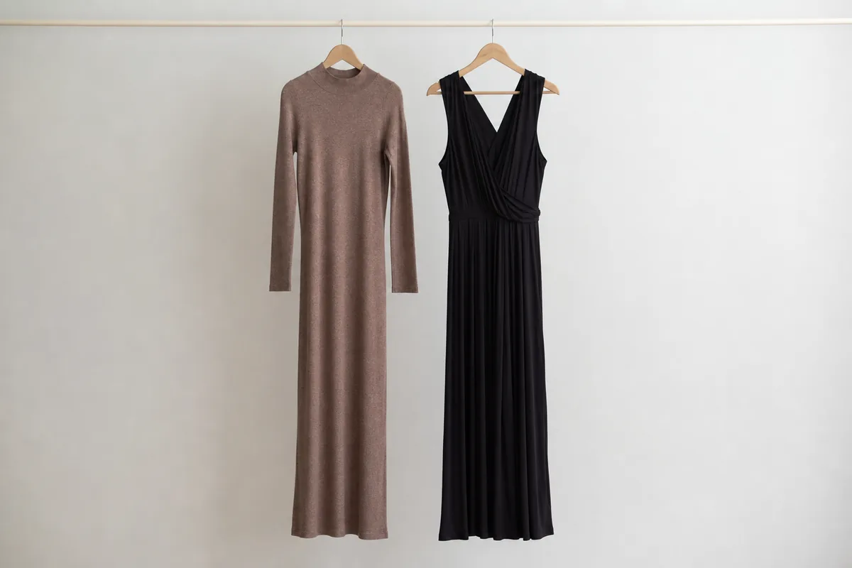 Vestido de punto y vestido largo oscuro colgados en un perchero