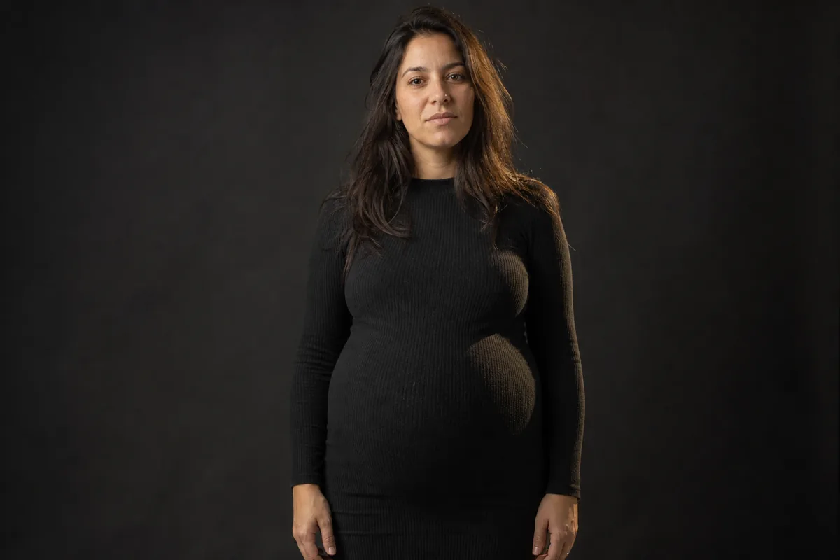 Embarazada de siete meses de frente en el estudio con vestido de punto ceñido