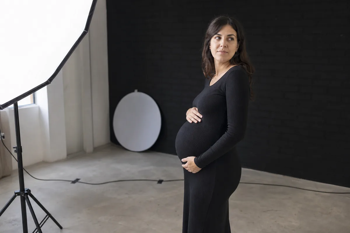 Sesión premamá en estudio con la ventana de luz visible en el encuadre